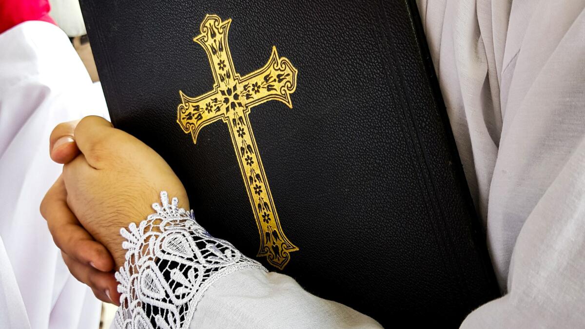 Hand hält Buch mit Kreuz