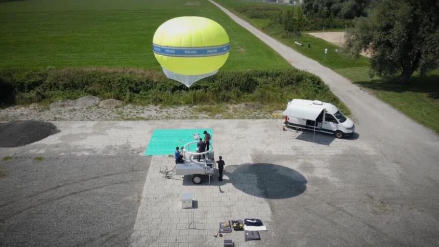 Das Bild zeigt einen gelben Heliumballon mit der Aufschrift "Polizei" sowie einen Anhänger und ein Begleitfahrzeug.