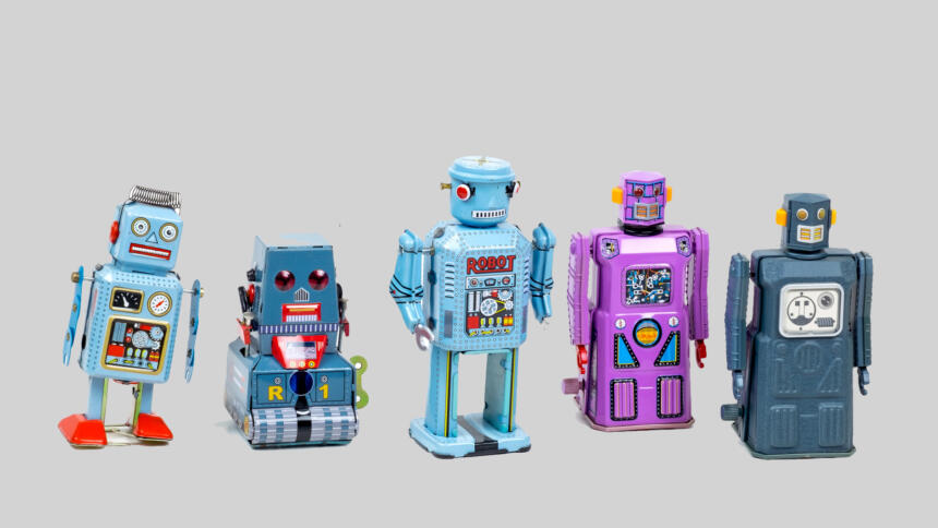 Fünf kleine bunte Spielzeugroboter stehen nebeneinander.