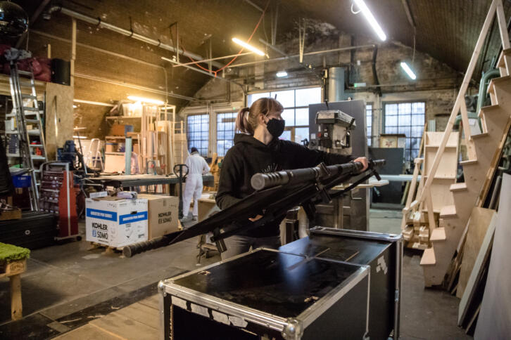 Eine Person steht in einer Werkstatt und hebt eine Krankentrage auf eine Kiste