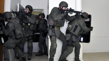 Das Bild zeigt dunkel gekleidete Männer in Uniformen und automatischen waffen, die einen Raum betreten haben und offenbar absichern.