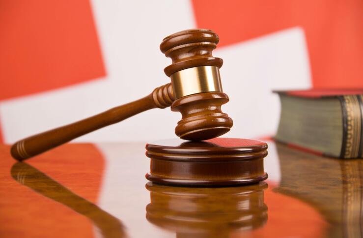 Gerichtshammer und Buch vor einer schweizer Fahne