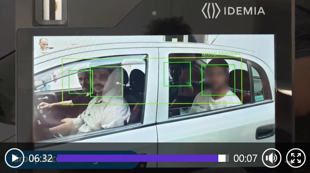 Das Bild zeigt vier Männer in einem Auto, die Gesichter sind dabei von grünen Rahmen umgeben. Es handelt sich um ein Foto eines digitalen Displays, das wiederum im Standbild eines Films zu sehen ist.