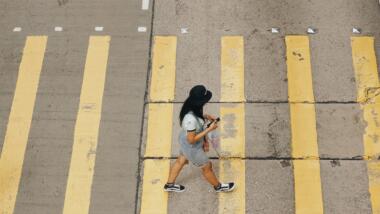 Frau mit Handy in der Hand läuft über gelben Zebrastreifen.