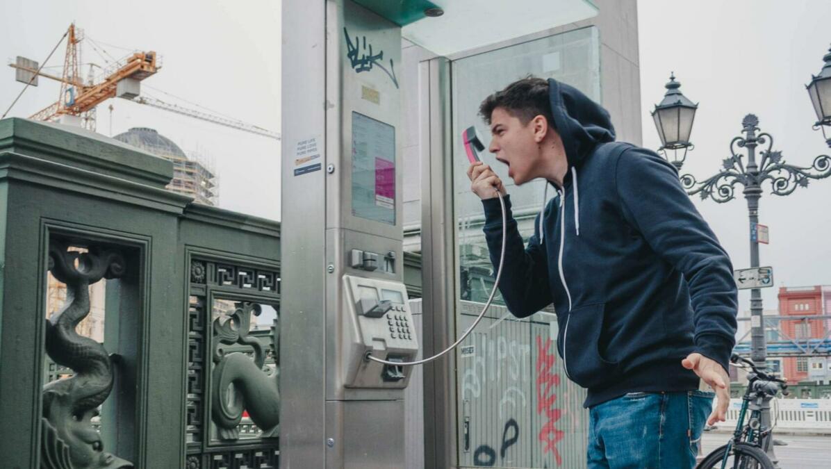 Mann schreit in Telefonhörer