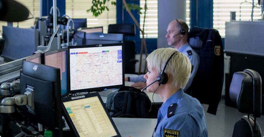 Das Bild zeigt einen Mann und eine Frau in Uniform und mit Headsets vor ihrem Monitor.