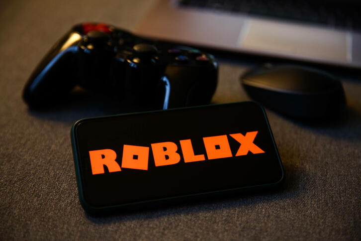 Smartphone mir Roblox Logo und Controller.