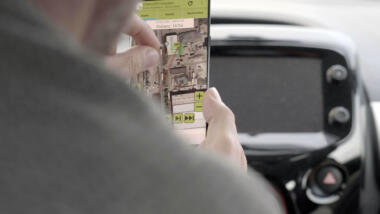 Eine Hand zoomt auf die Schaltfläche eines Smartphones heran, auf der ein GPS-Signal zu sehen ist