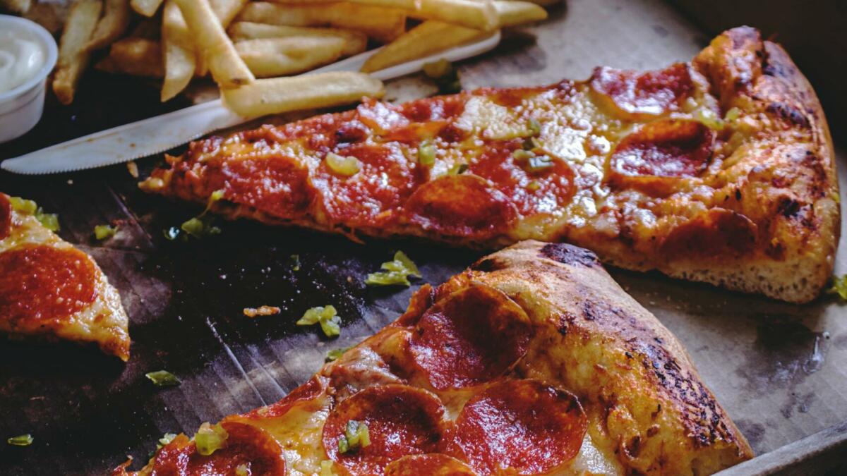 Kalte Pizza und Pommes in einem Karton