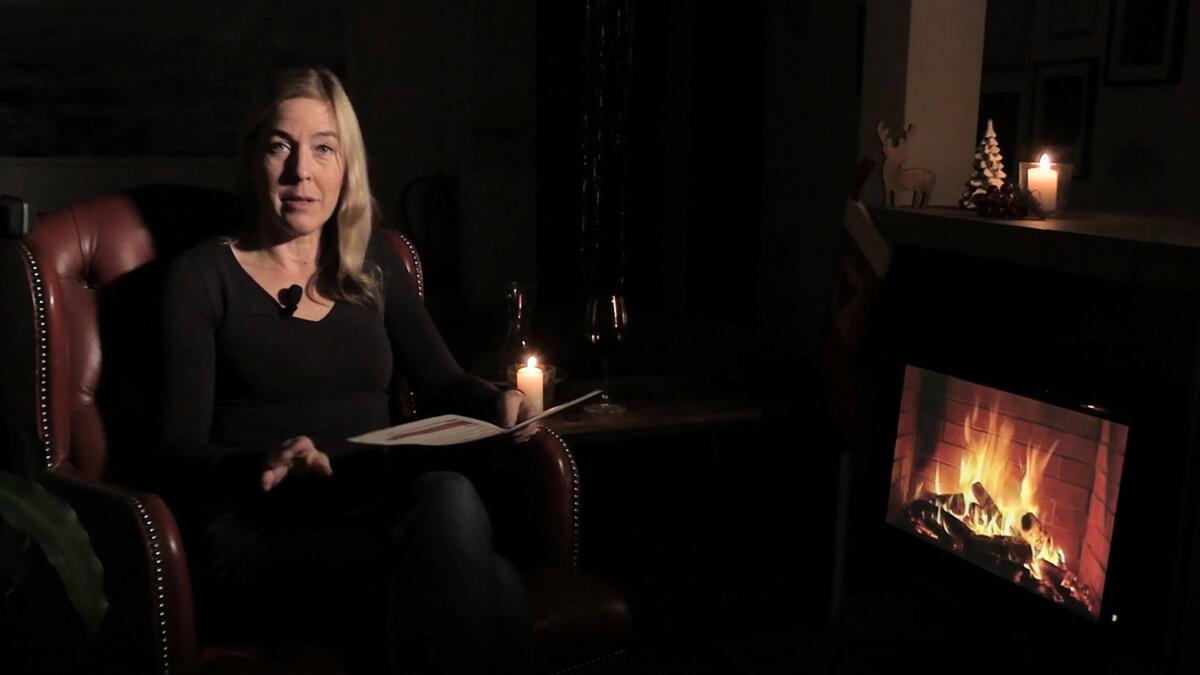 Blonde Frau auf Ohrensessel an Kamin