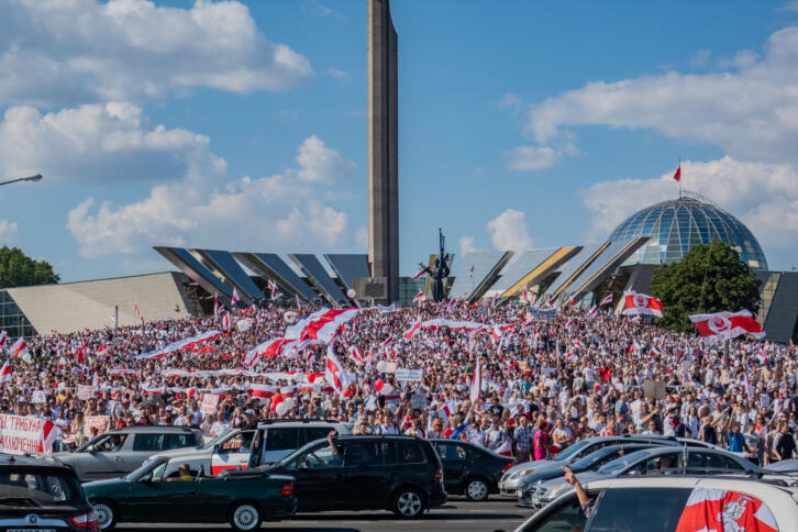 Das Bild zeigt Tausende Menschen auf einer Demonstration, sie tragen weiß-rote Banner.