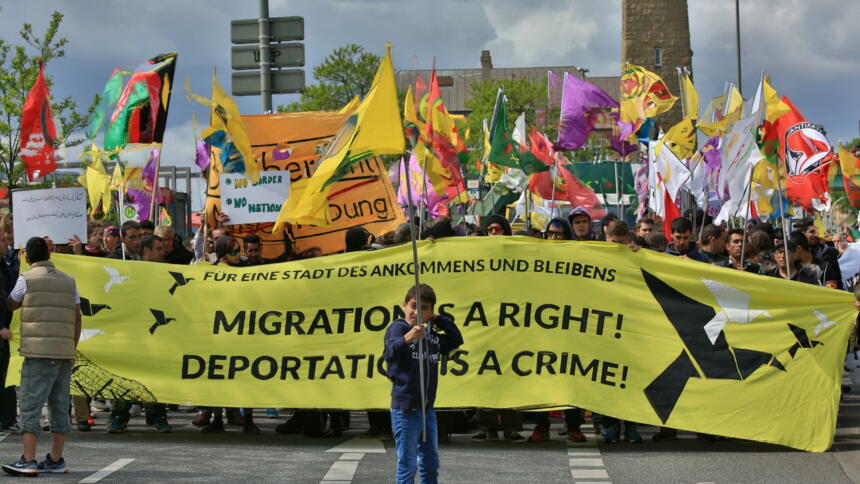 Eine Demonstration gegen Abeschiebung, Menschen tragen ein gekbes Banner "Migration is a right"