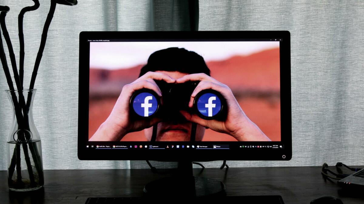 Mann mit Fernglas, auf dem die Facebook-Logos zu sehen sind