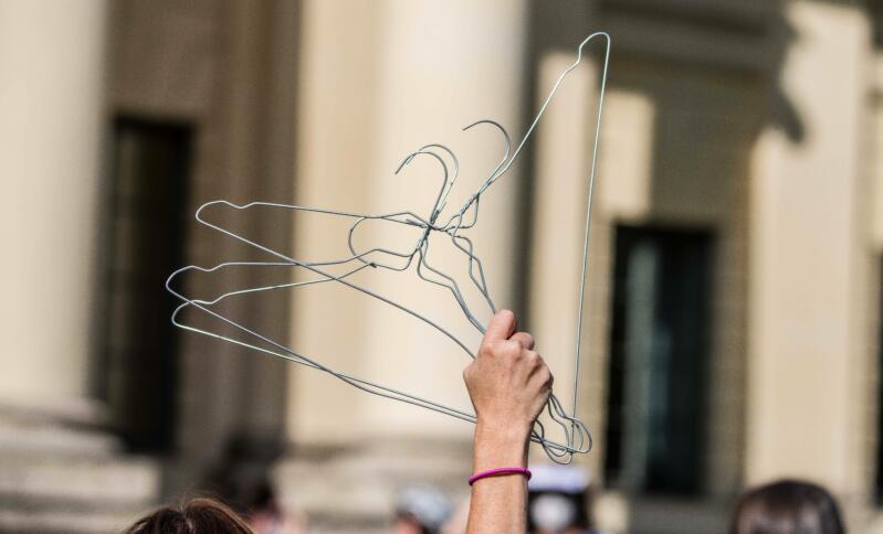 Eine Person hält Metallkleiderbügel in die Luft