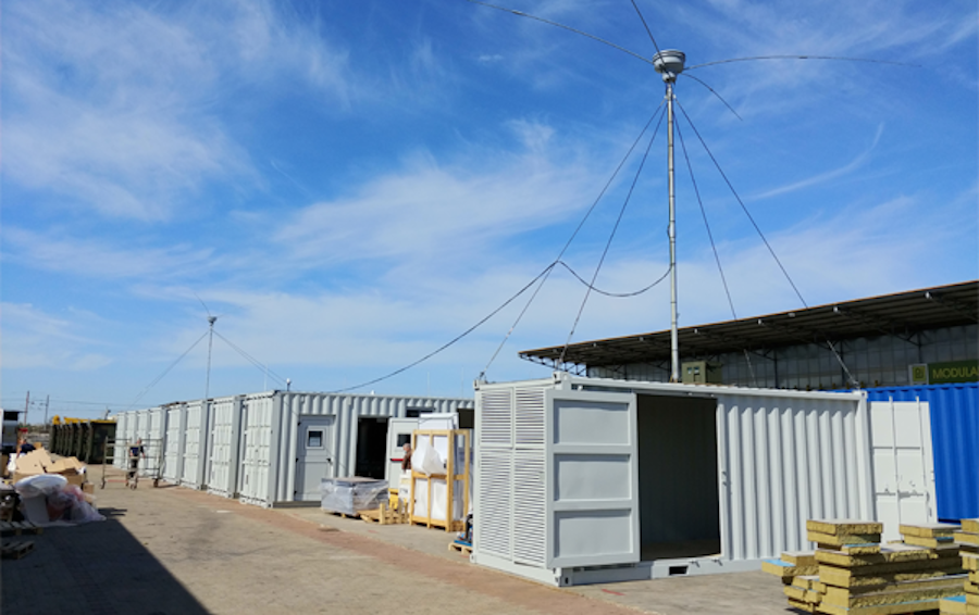 Das Bild zeigt mehrere graue Container, auf denen eine Antenne montiert ist.