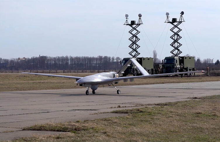 Das Bild zeigt eine Drohne "TB2" auf einem Rollfeld or Lastwagen mit Antennen.