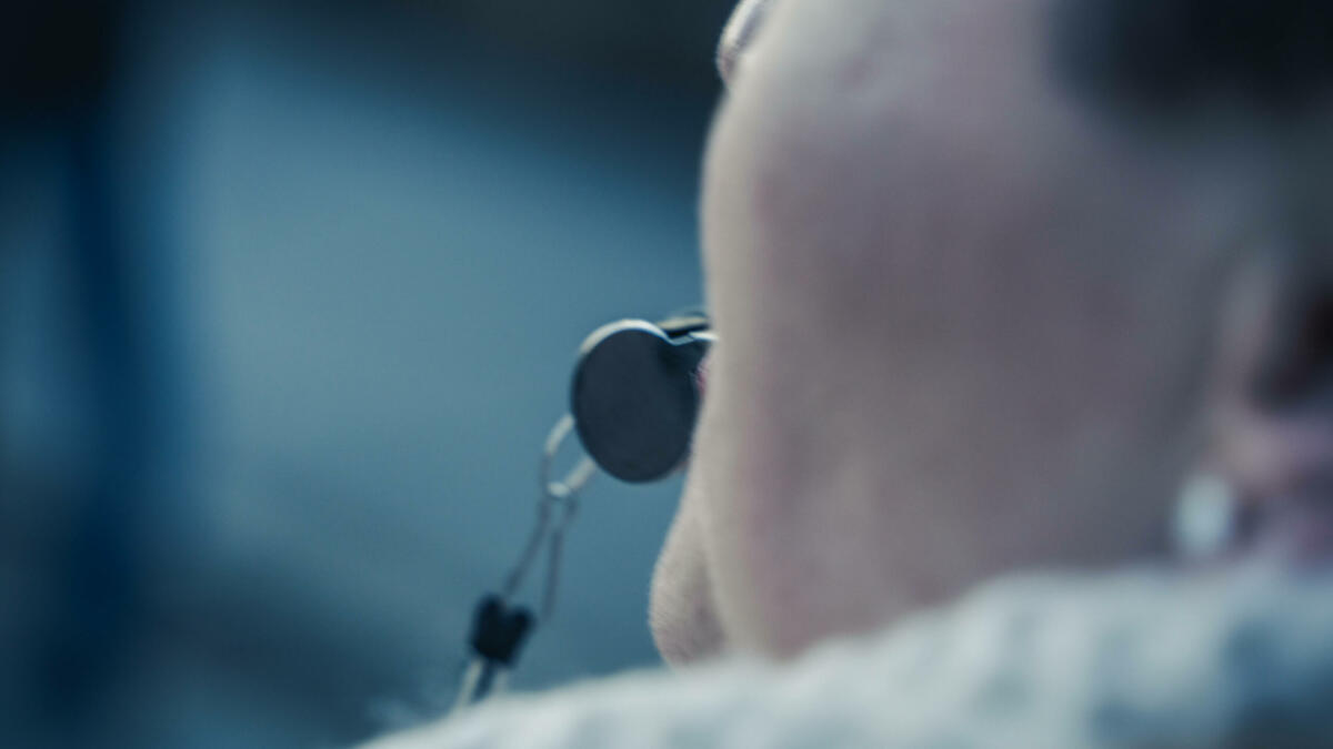 Mensch mit silberner Trillerpfeiffe im Mund