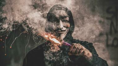 Mensch mit Anonymous-Maske und Pyrotechnik in der Hand