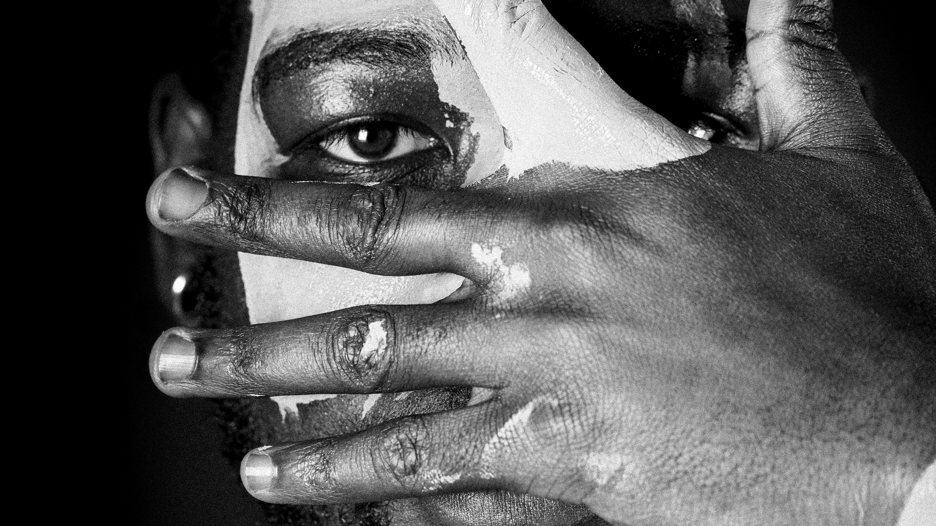 Nahaufnahmen von einem Mann. Er hält sich eine Hand vor das Gesicht. Ein Auge ist zu sehen.