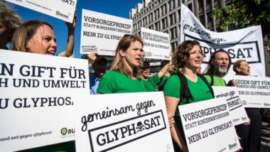 Eine Demonstartion gegen die Verwednung von Glyphosat. Die Personen auf dem Bild tragen grüne T-SHirts. Sie halten Schilder in der Hand. Auf den Schildern steht: "Gemeinsam gegen Glyphosat" und Vorsorgeprinzip statt Konzerninteressen! Nein zu Glyphosat! Die Personen haben den Mund geöffnet und scheinen zu rufen.