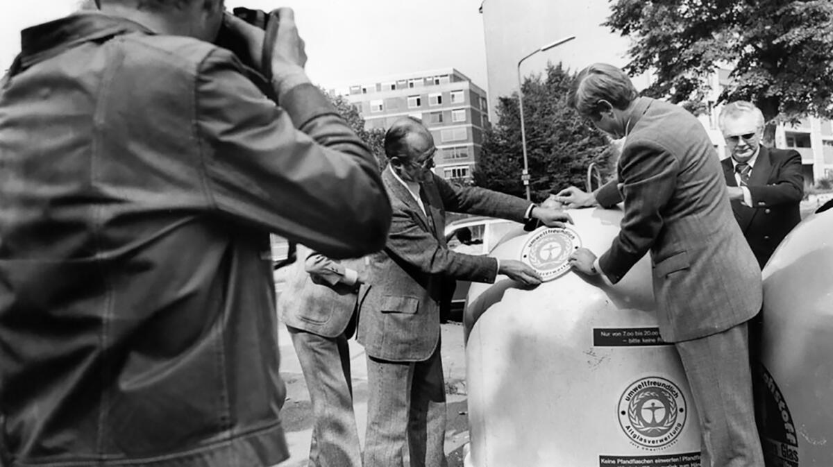 Erster Präsident des Umweltbundesamtes, H. Freiherr von Lersner beklebt einen Container mit dem Umweltzeichen.