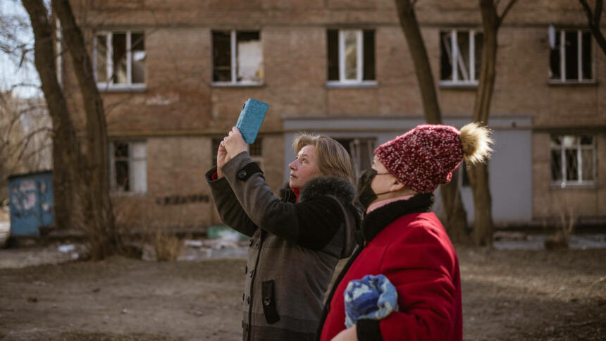 Zivilist:innen dokumentieren Kriegsschäden in Kiew.