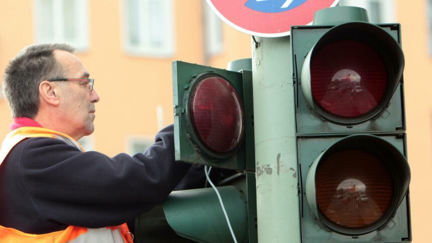 Techniker repariert eine defekte Verkehrsampel an einer belebten Straßenkreuzung in Berlin