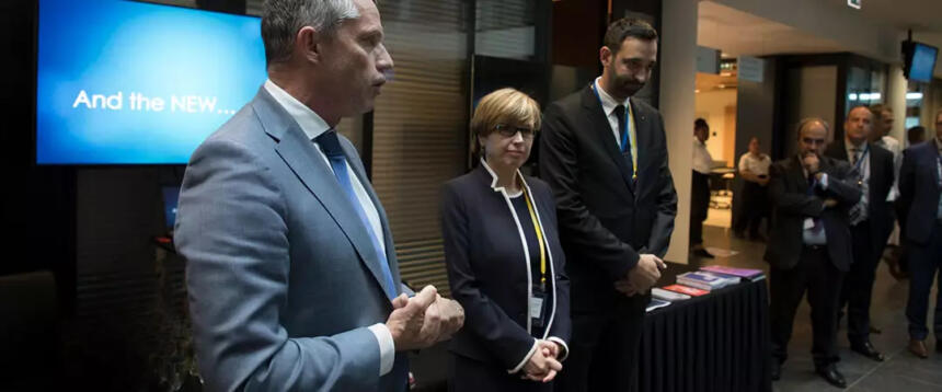 Das Bild zeigt drei Personen (in der Mitte Catherine De Bolle) auf einer Pressekonferenz vor einer Leinwand mit den Worten "And the NEW...".