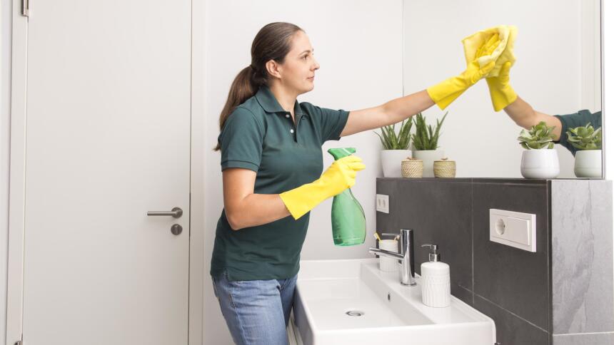 Eine Person reinigt einen Badezimmer-Spiegel