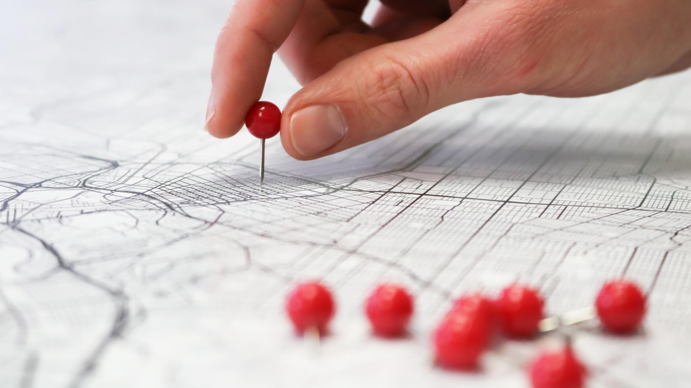 Hand setzt Pin auf Karte