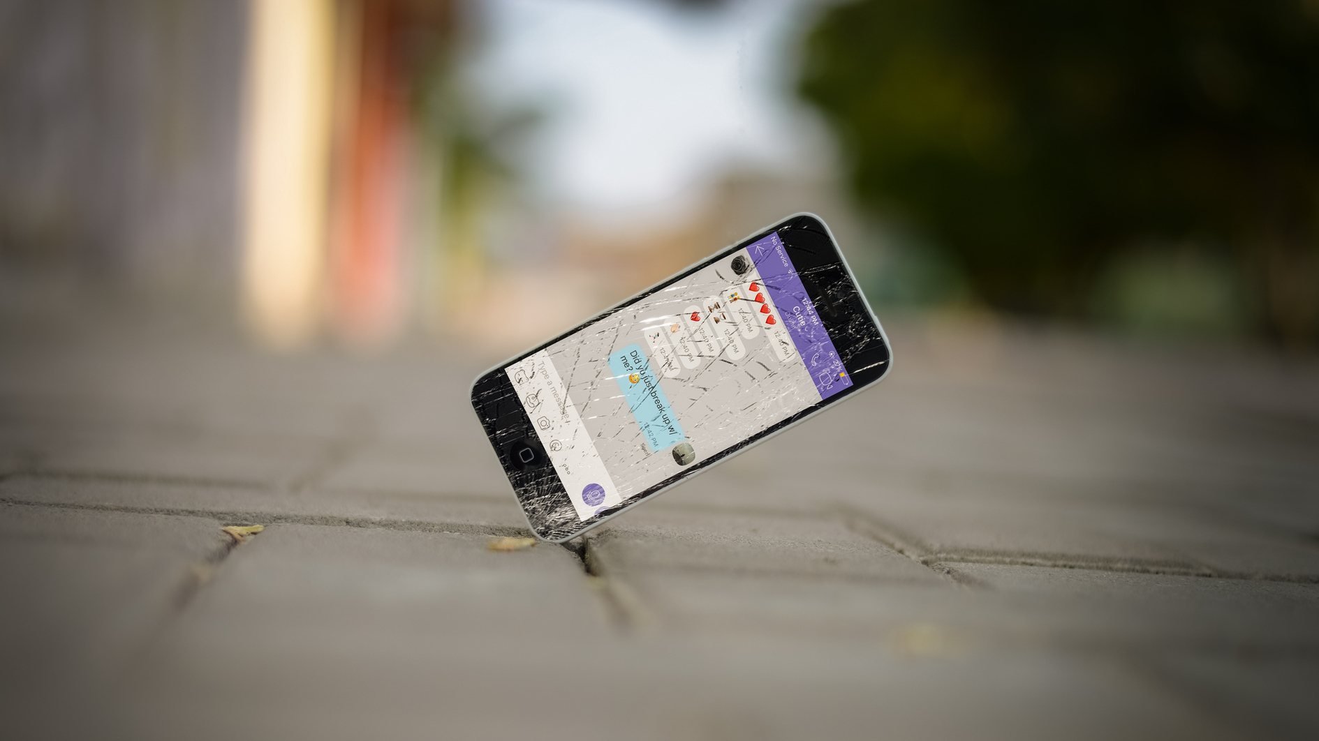 Ein Handy kommt mit zersplittertem Display auf dem Boden auf.