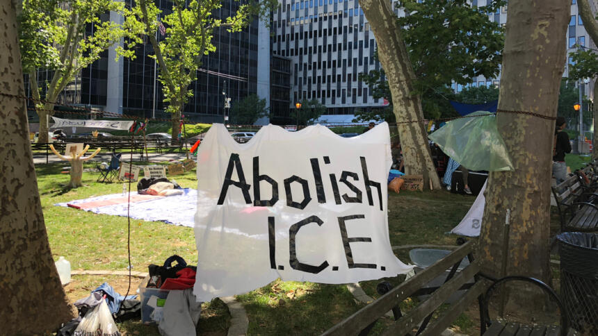 Ein Protestcamp vor dem ICE-Gebäude, im VOrdergrund ein Banner mit der Aufschrift "Abolish ICE".