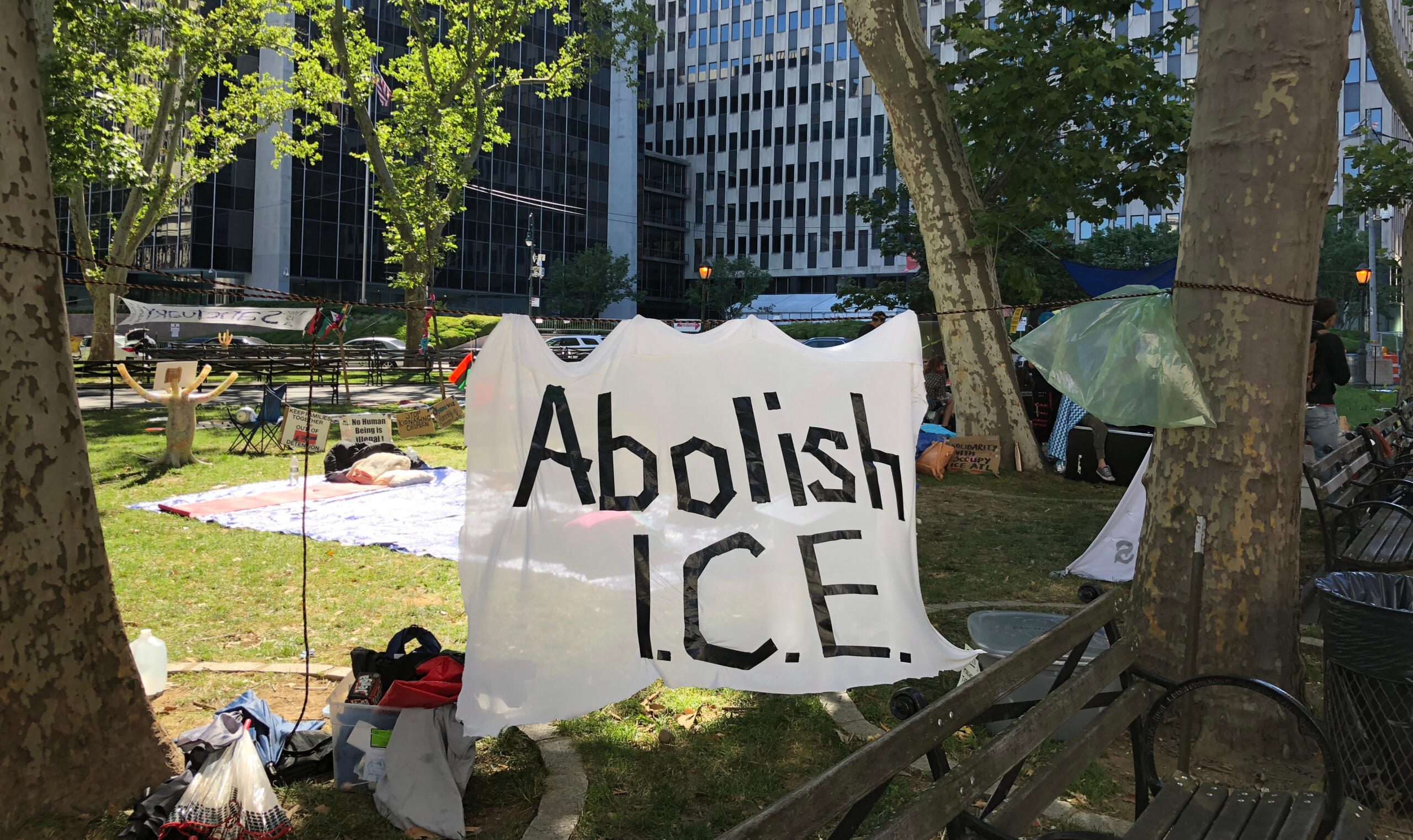 Ein Protestcamp vor dem ICE-Gebäude, im VOrdergrund ein Banner mit der Aufschrift "Abolish ICE".