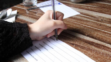 Hand schreibt auf Papier Kontaktdaten