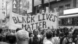 Demonstration auf der Straße, Banner mit Schriftzug "Black Lives Matter"