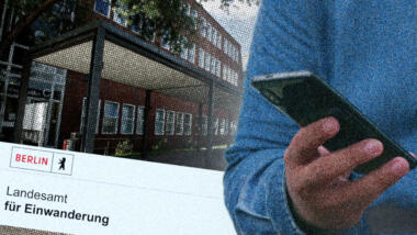 Person hält Handy, im Hintergrund Landesamt für Einwanderung Berlin