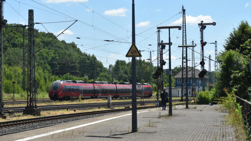 Eine Person auf einem sonst leeren Bahnsteig in Dillenburg, an der ein Zug vorbeifährt.