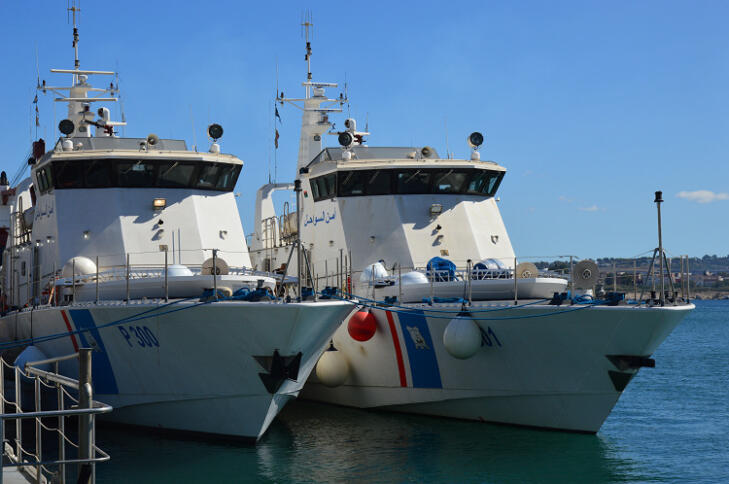 Zwei große weiße Patouillenboote nebeneinander im Hafen angebunden.