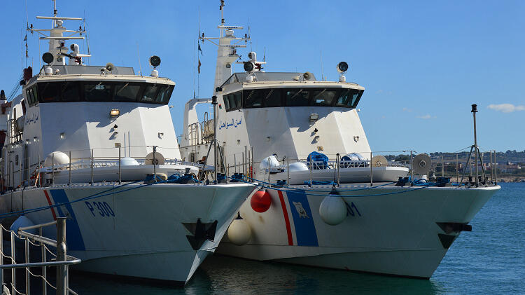 Zwei große weiße Patouillenboote nebeneinander im Hafen angebunden.
