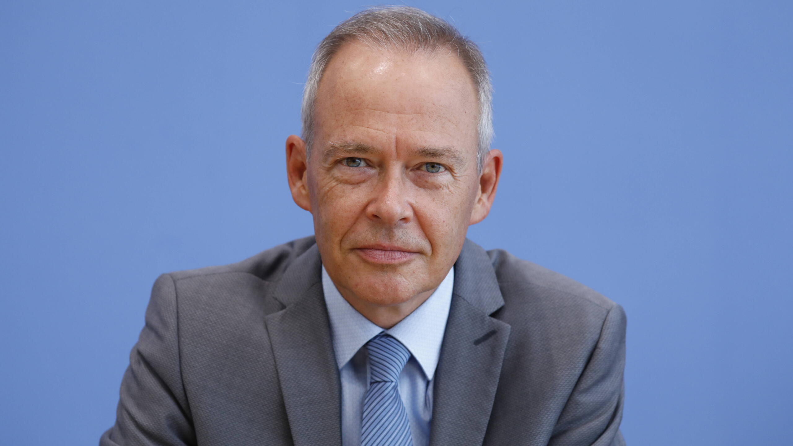 Ein Mann im Anzug vor blauem Hintergrund