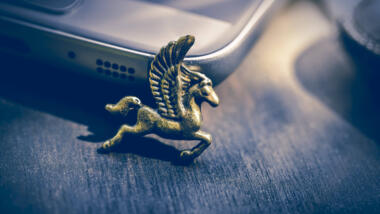 Eine bronzene Pegasusfigur lehnt an einem Smartphone