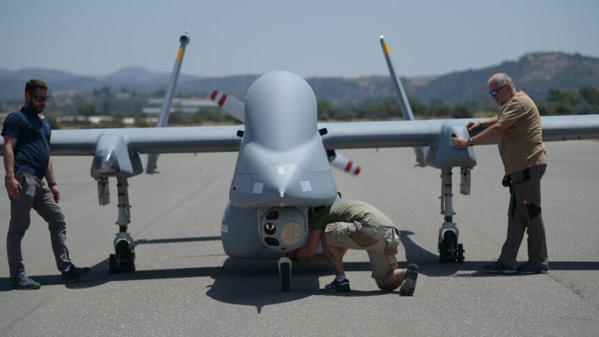 Eine Drohne von vorn auf dem Rollfeld, dabei insgesamt drei Techniker am Bug und an jedem Flügel.