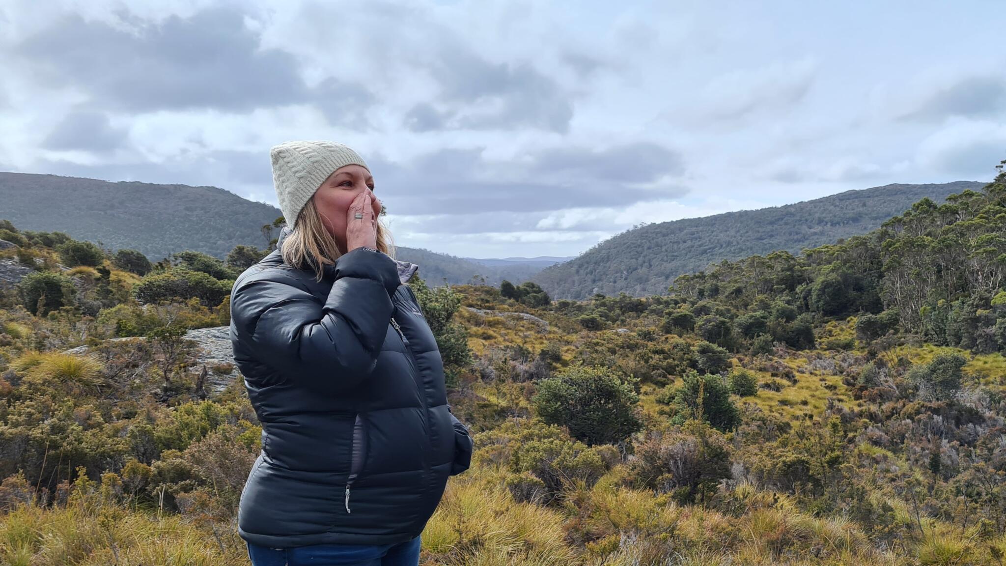 Frau steht in den Bergen und ruft laut