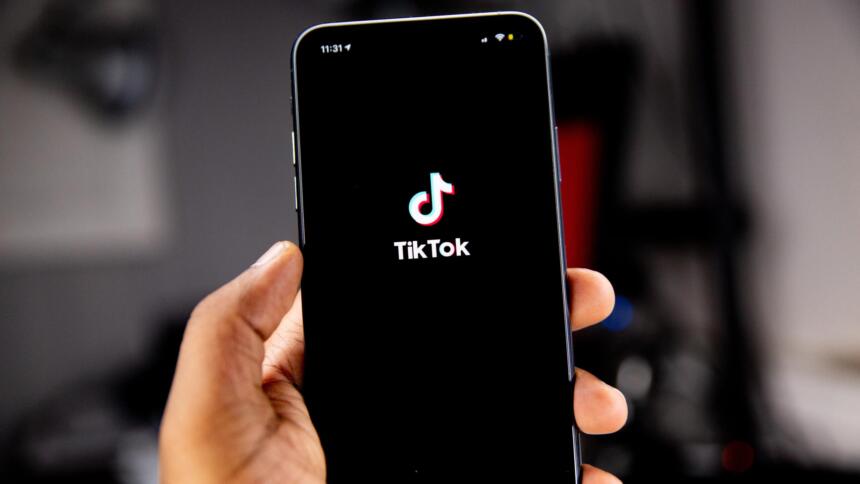 Eine Person hält ein Smartphone in der Hand, auf dem das TikTok-Logo angezeigt wird