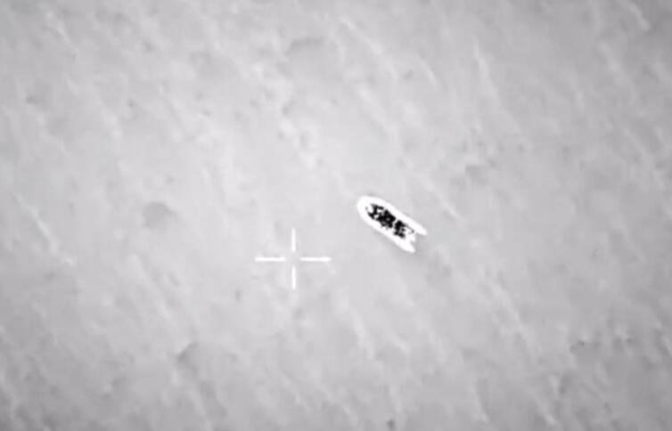 Eine verschwommene schwarz-weiß-Luftaufnahme eines Schlauchootes, daneben ein Kreuz des Kamera-Displays.