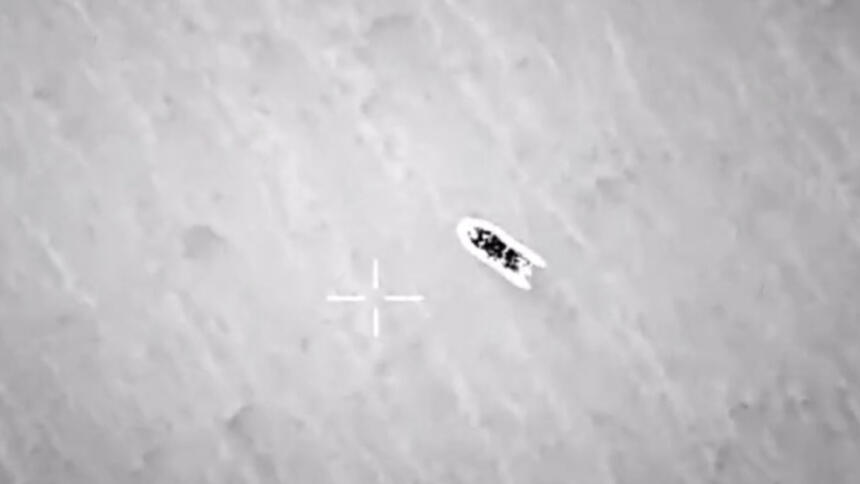 Eine verschwommene schwarz-weiß-Luftaufnahme eines Schlauchootes, daneben ein Kreuz des Kamera-Displays.