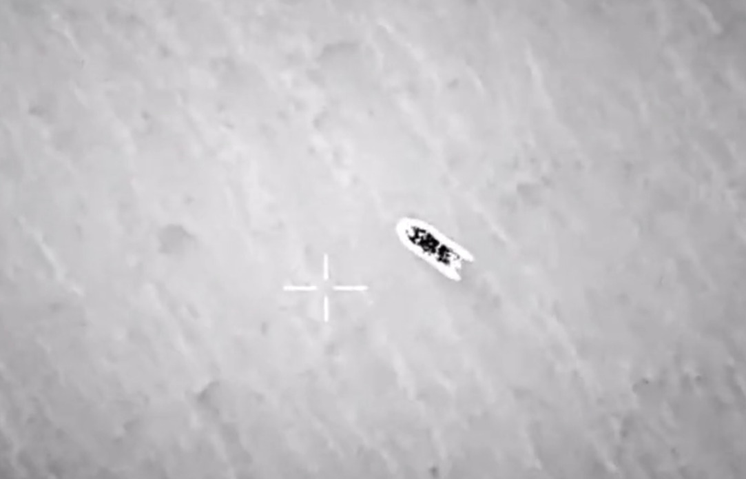 Eine verschwommene schwarz-weiß-Luftaufnahme eines Schlauchootes, daneben ein Kreuz des Kamera-Displays.