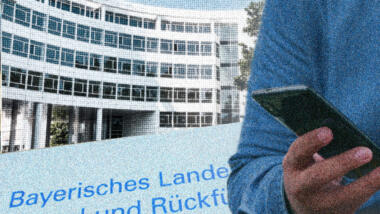 Das Bayerische Landesamt für Asyl in München, im Vordergrund hält jemand ein Smartphone in der Hand