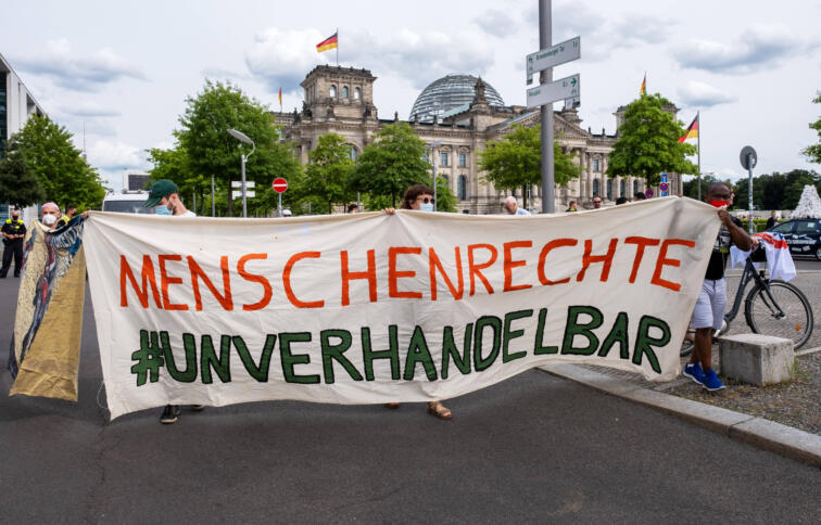 Der Slogan "Menschenrechte #unverhandelbar" steht auf einem Protestbanner. Im Hintergrund ist das Reichstagsgebäude zu sehen