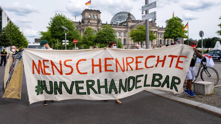 Der Slogan "Menschenrechte #unverhandelbar" steht auf einem Protestbanner. Im Hintergrund ist das Reichstagsgebäude zu sehen